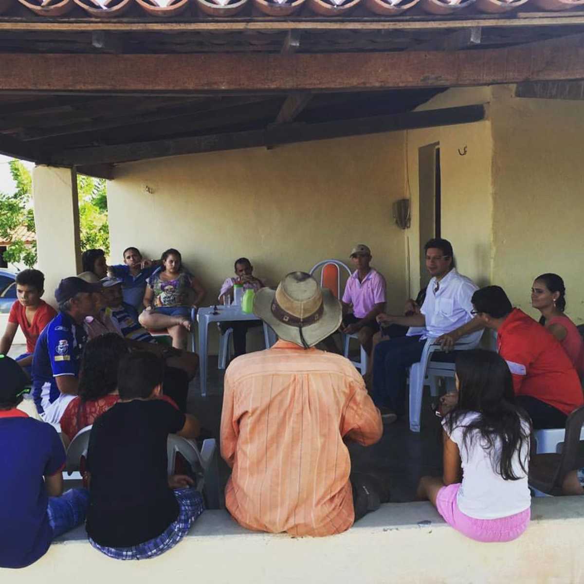 Grupo de pessoas conversam em alpendre de casa