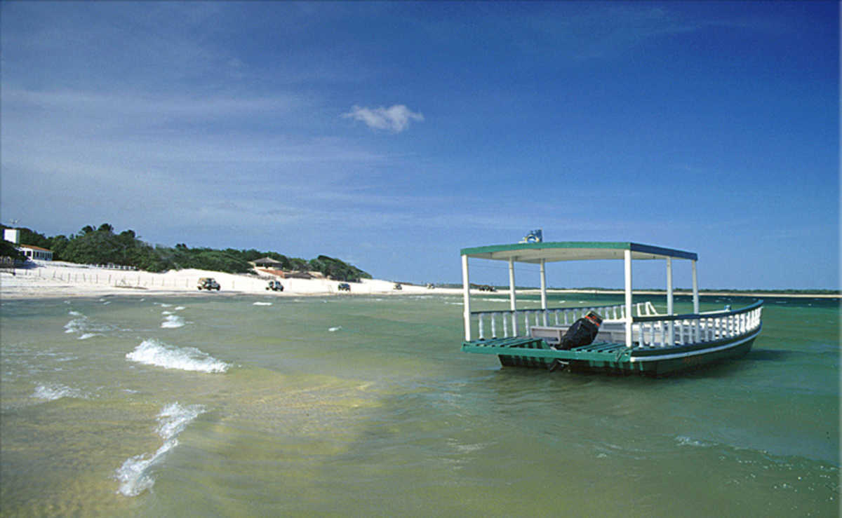 Um barco sobre as águas da Lagoa de Jijoca com bugres ao fundo