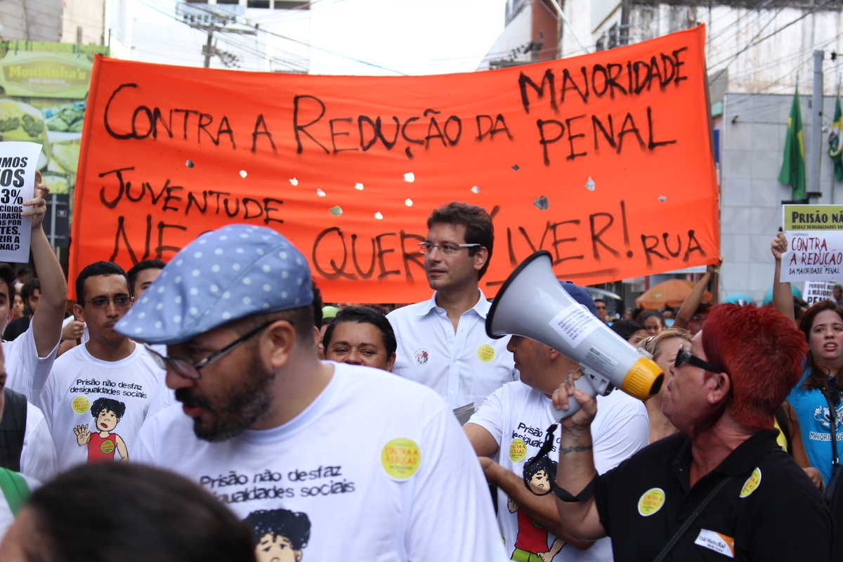 Dezenas de pessoas com cartazes, faixas e megafone em caminhada pelo Centro de Fortaleza