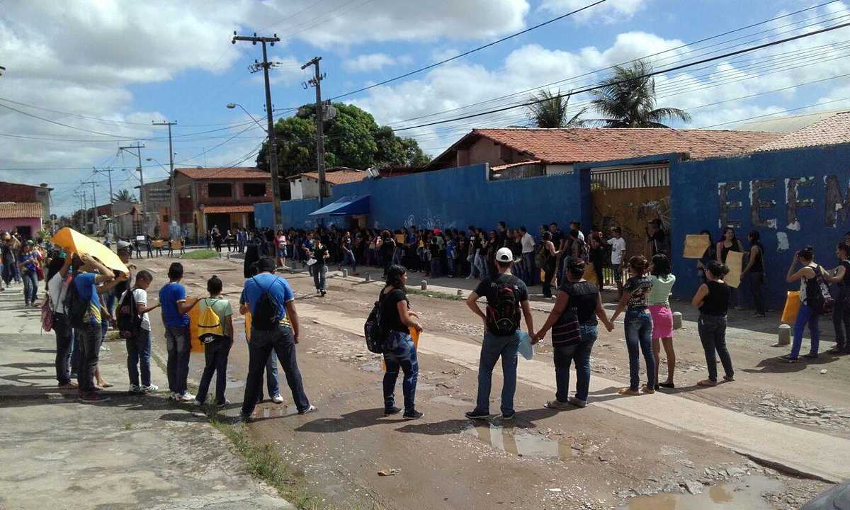 Estudantes e professores seguram cartazes em frente a escola no bairro Canindezinho, em Fortaleza