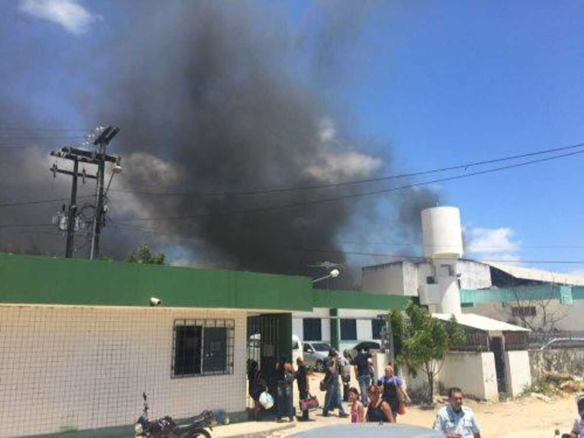 Circulação de pessoas em frente a um prédio, onde fumaça indica incêndio